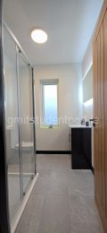 Bathroom with large LED backlit mirror, vanity unit, toilet and shower.